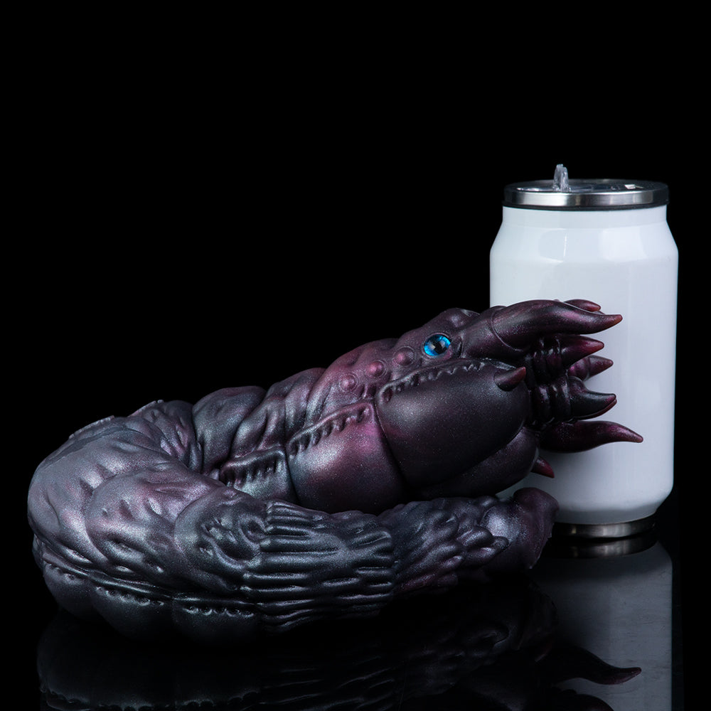 Purple alien creature toy curled beside a white canister, glossy textured surface