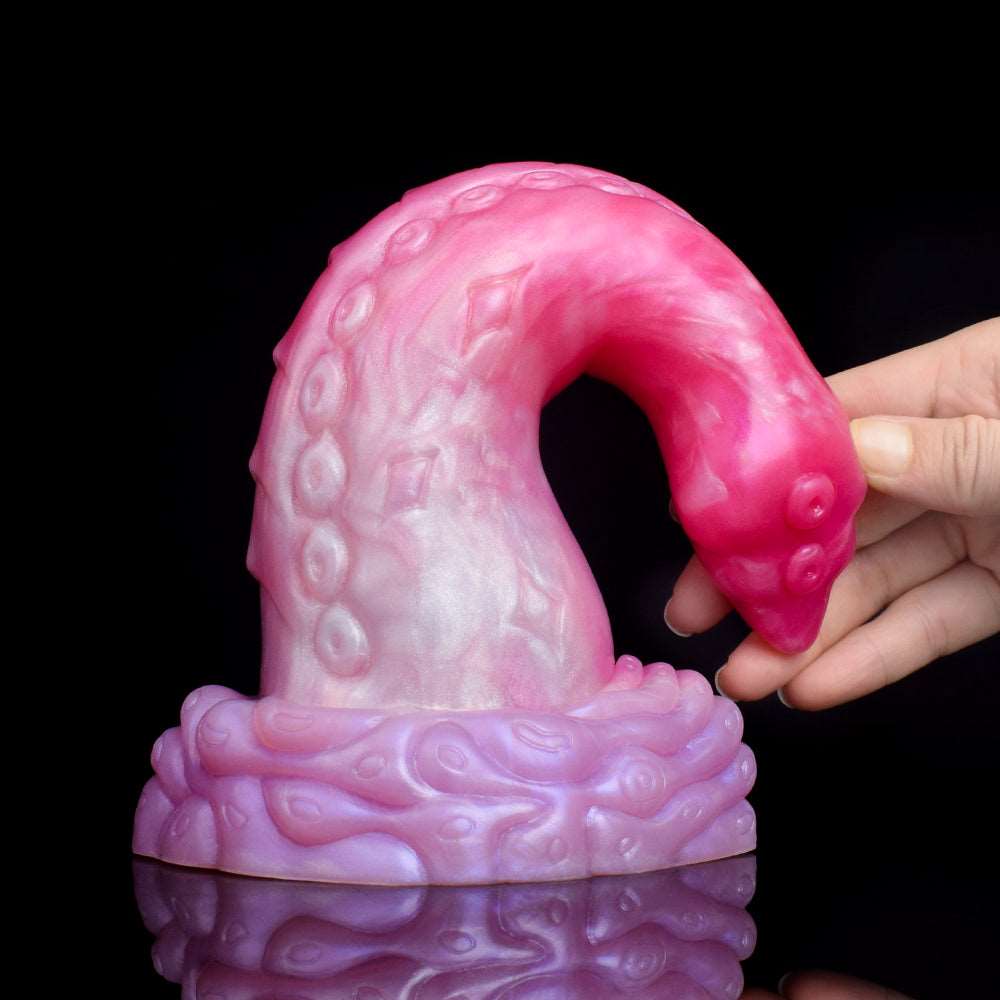 Pink curved octopus tentacle butt plug, fantasy dildo design, held in hand