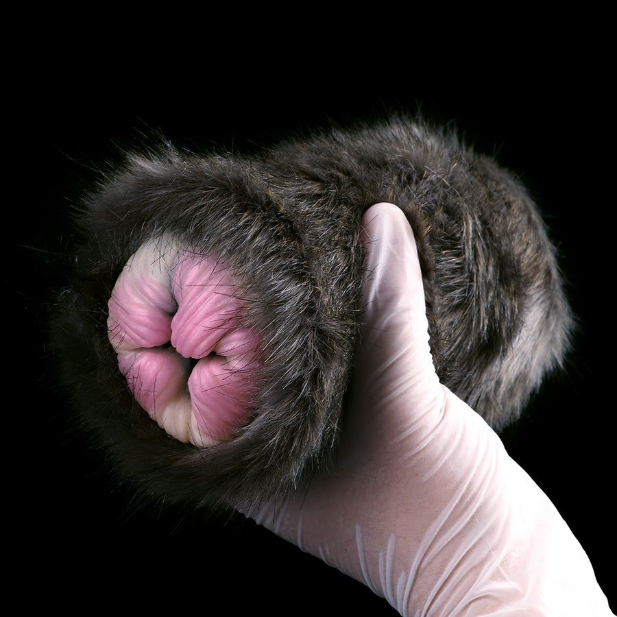 Furry plush cat-shaped sleeve with pink inner opening, held in white glove