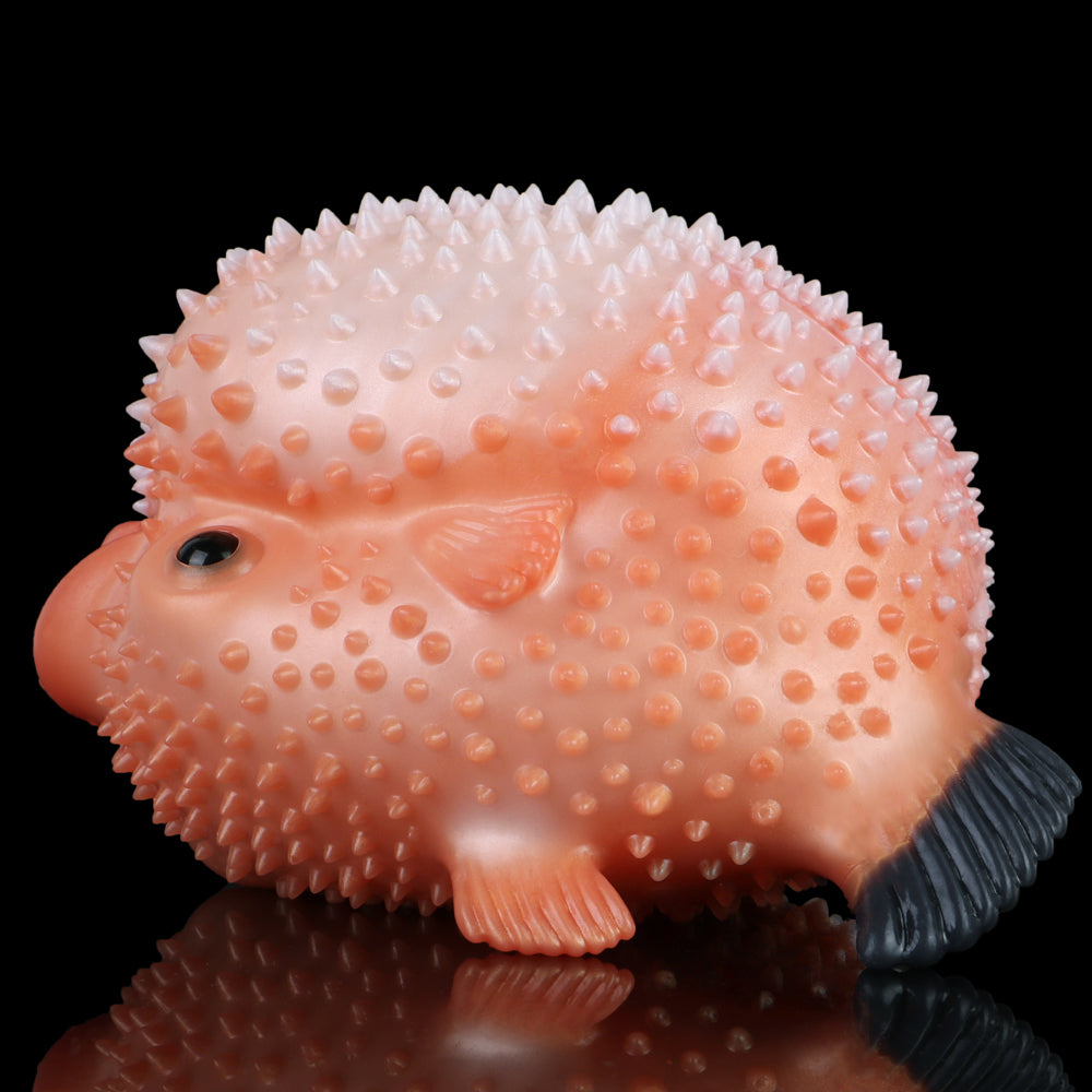 Close-up of pink pufferfish sex toy with spiky nodules, black eye, and tail