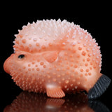 Close-up of pink pufferfish sex toy with spiky nodules, black eye, and tail