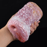 Hand holding pink canine fleshlight stroker, textured sleeve with open end.