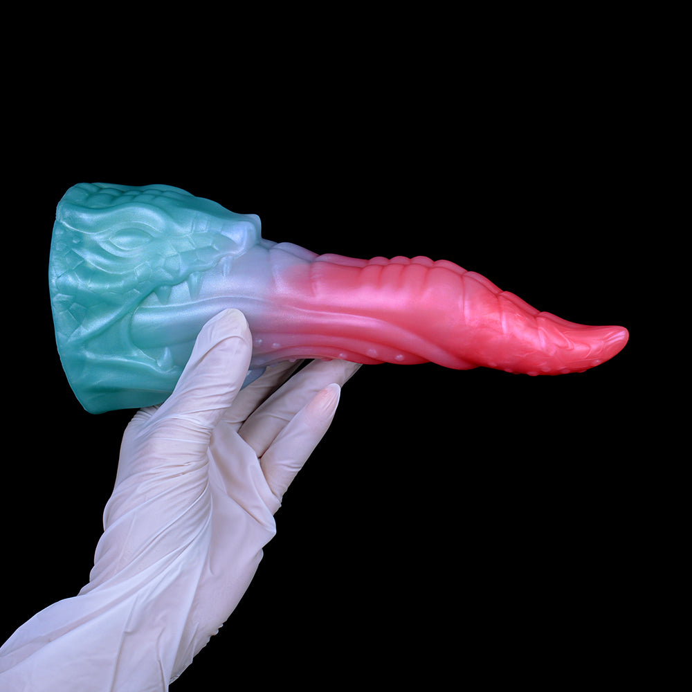 Dragon-style dildo in white-gloved hand, light-blue base and pink tapered end.