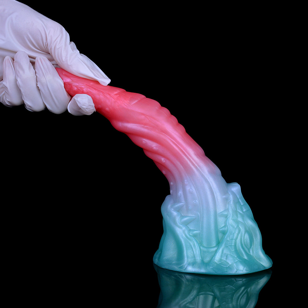 Close view of pink-and-light-blue dragon-style dildo held by white-gloved hand.