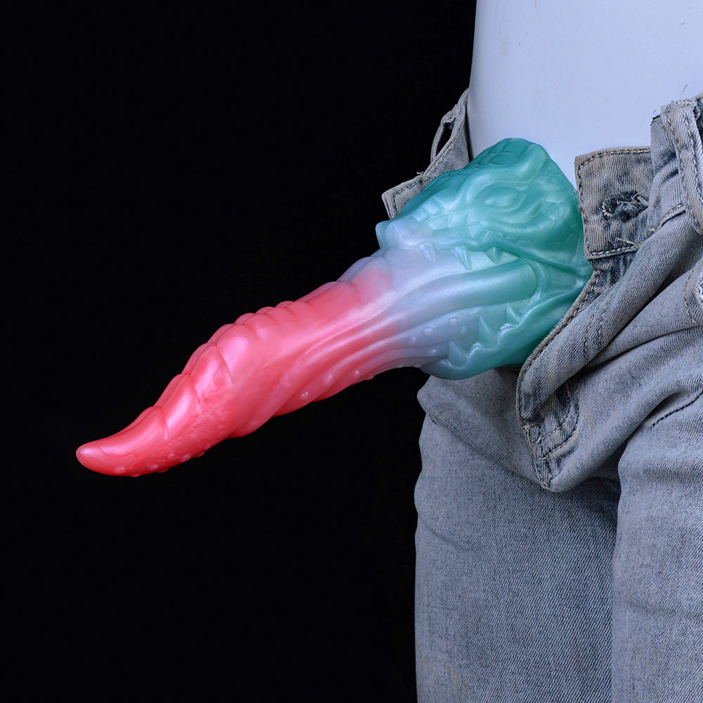 Pink-and-light-blue dragon-style dildo positioned at waistband, near denim jeans.