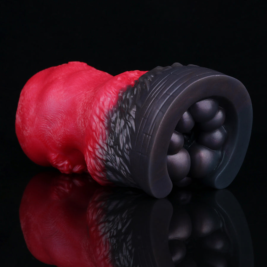 Red and black pleasure toy with side angle view and rounded ball-textured tip.