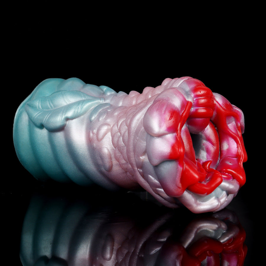 Dragon-shaped silicone masturbator in teal and pink with scaled texture and red inner tip.
