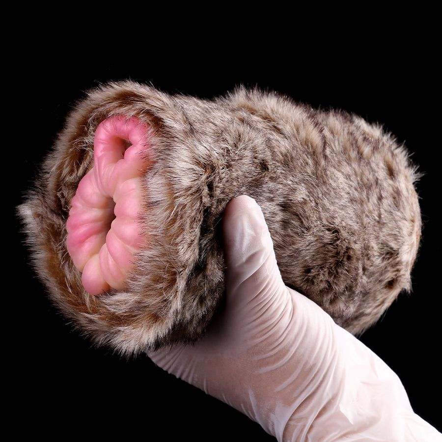 Furry dual-hole fleshlight with pink opening and gloved hand inserting beige part.