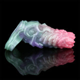 Cock sleeve extender on a base, shown from the left; iridescent pink, purple and turquoise
