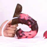 Hand holding horse-cock toy with brown base and attached white tube, pink flow
