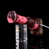 Horse-cock toy producing a pink stream toward a clear cup, brown textured base