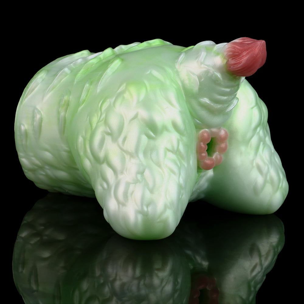 Green silicone butt plug with pink insert tip, curled side view, ridged details visible.