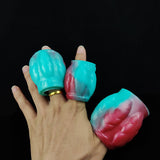 Teal and pink dragon knot sheath sleeve extender held in fingers, open end visible