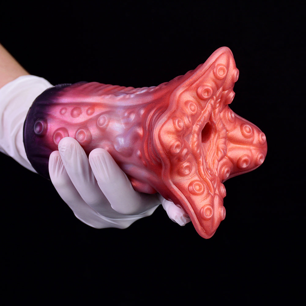 Red tentacruel-style stroker head with suction-cup bumps, held in white glove