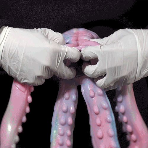 Pastel octopus figurine held by white-gloved hands, showing tentacles