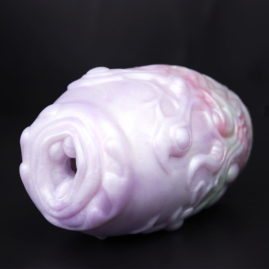 Pink-and-white dragon egg-style sex toy angled view showing embossed bumps