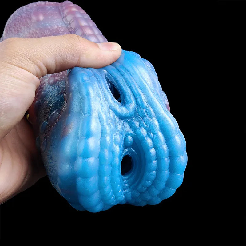 Hand holding blue dragon-shaped male masturbator with two rounded holes on the head