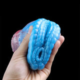 Hand holding blue dragon male stroker end, ridged texture and circular opening