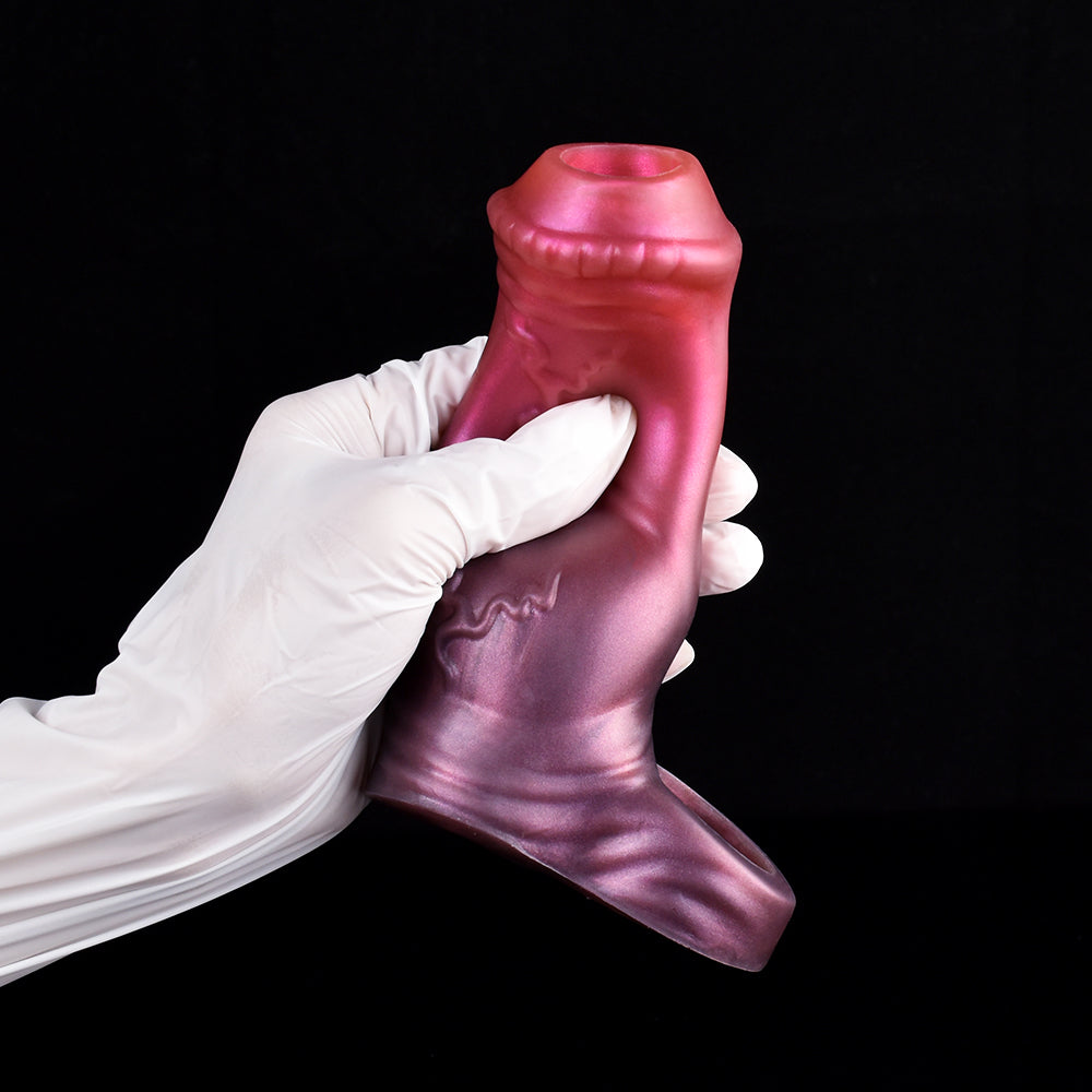 Pink penis extender sleeve with horse-knot embossing, held by white-gloved hands