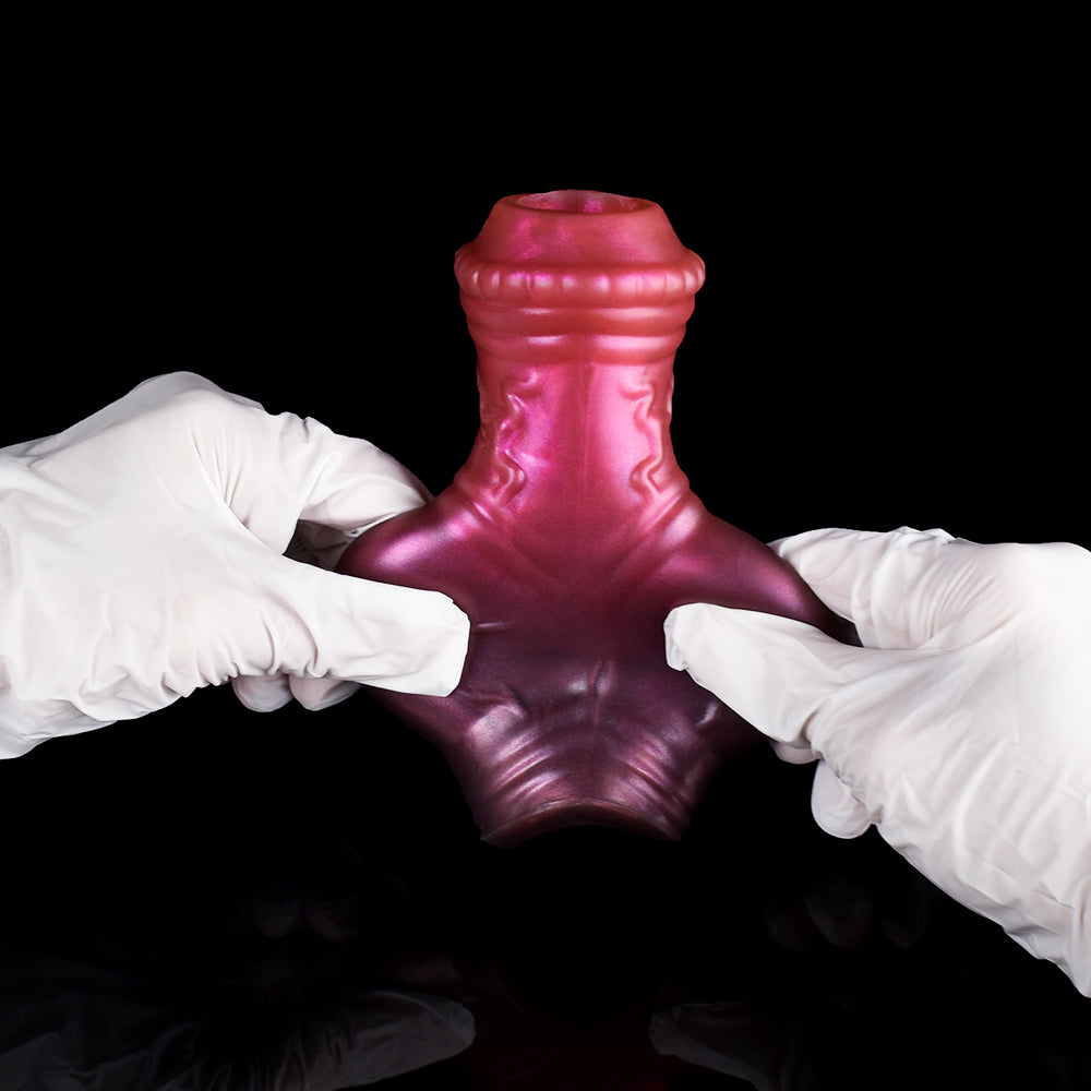 Pink horse-knot penis extender sleeve held flat, ridged texture and flared opening