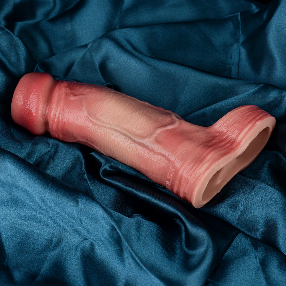 Light pink cock extender sleeve with scrotum ring lying on fabric, open end