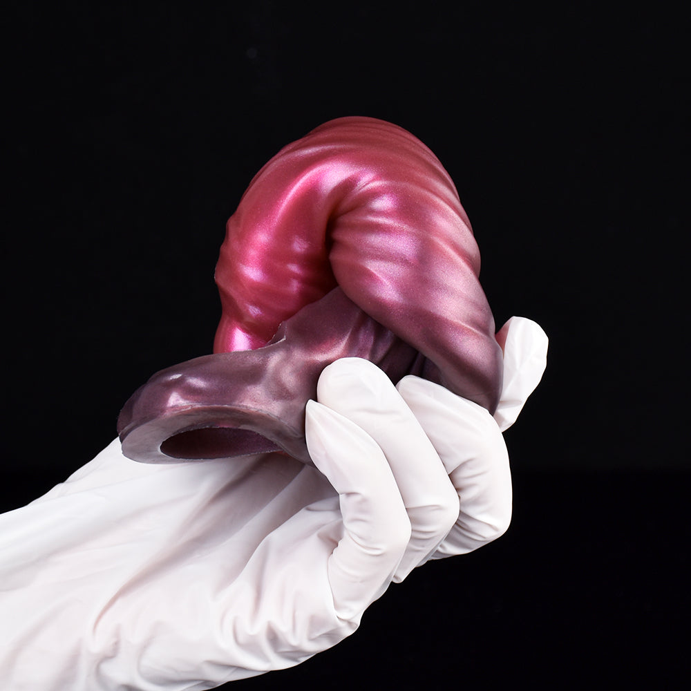 Magenta-pink cock sleeve extender close-up, textured surface held by white gloves