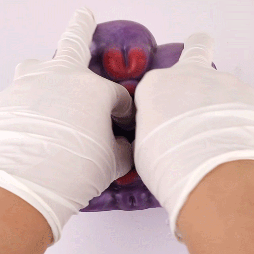 Purple silicone novelty toy held by white-gloved hands, red inner detail visible