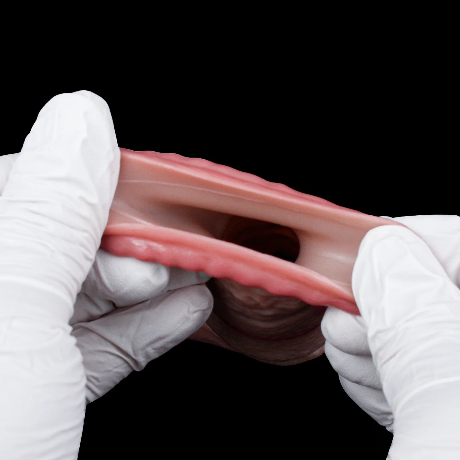 Textured pink cock sleeve/penis sheath held open in white gloves, translucent fabric
