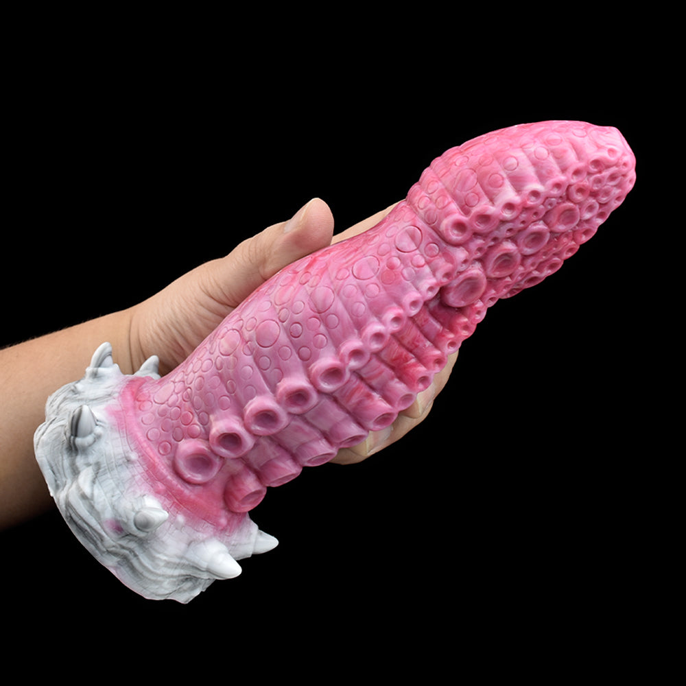 Pink monster tentacle vibrator held in hand; textured surface and white base with fins