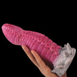 Pink monster tentacle vibrator stretched in hand; textured body and white base fins