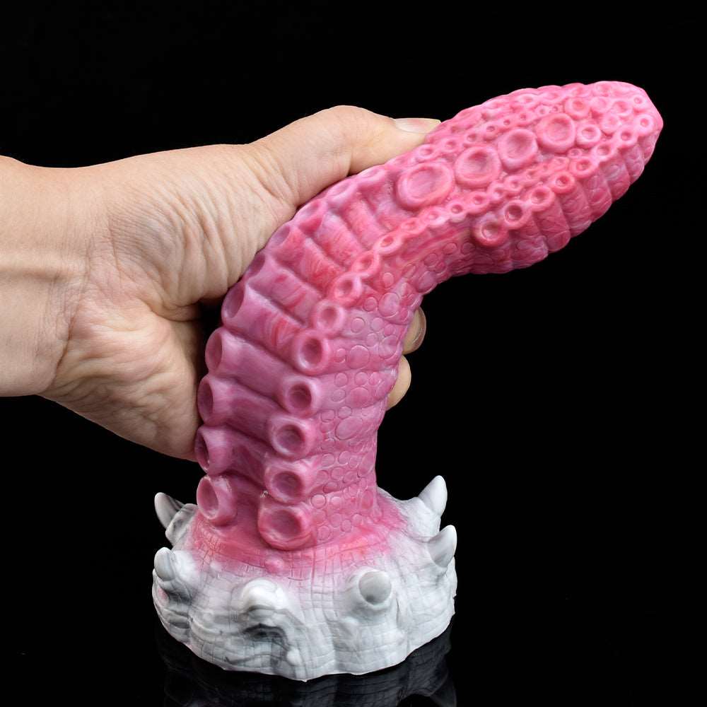 Pink monster tentacle vibrator in hand, showing ridged texture and white base details