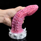 Pink monster tentacle vibrator in hand, showing ridged texture and white base details