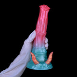 Dildo with demon horns standing upright, pink top and teal base with two orange horns