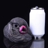 Animal-shaped dual-hole vibrating toy next to tall cylinder, textured dark gray