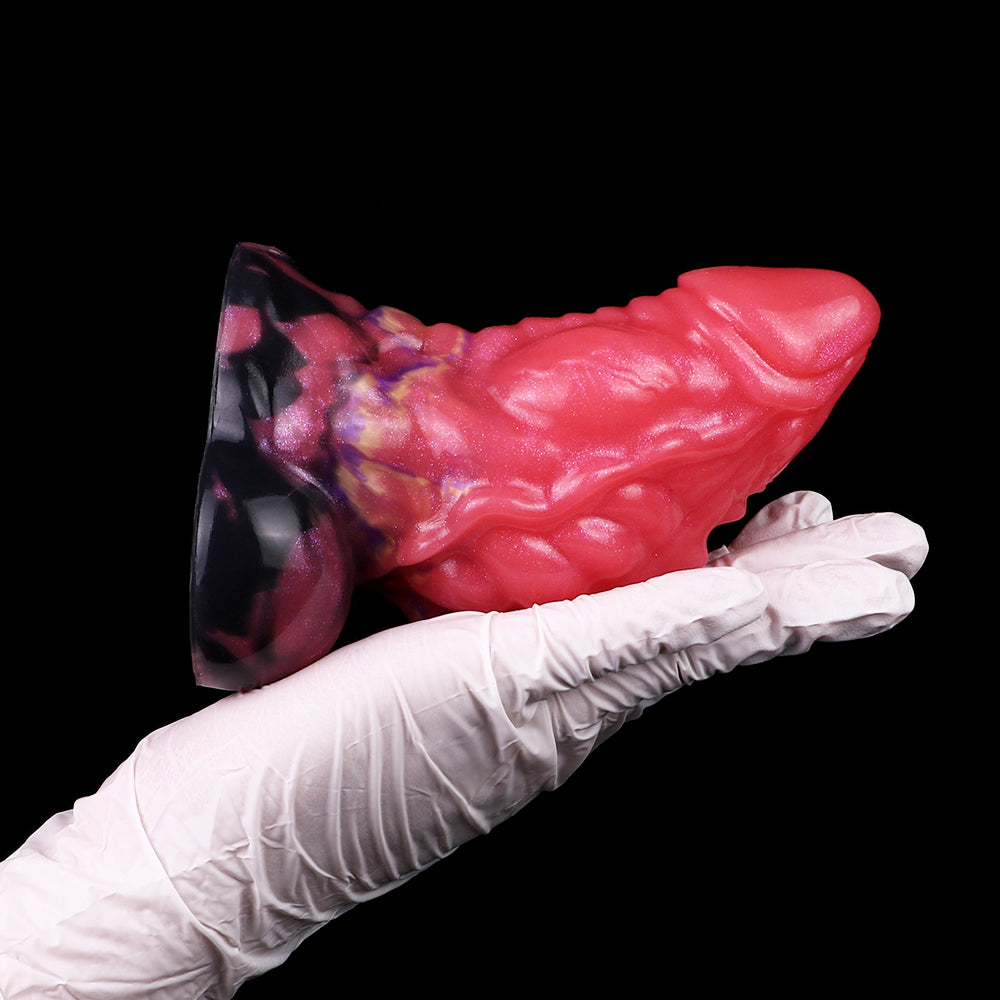 Anal plug close-up: glossy pink dragon body with dark patterned insert fin