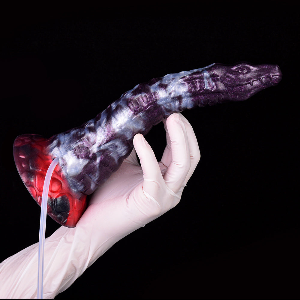 Gloved hand holding purple-and-white reptile-pattern dildo with clear suction tube