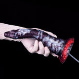 Gloved hand holding purple-and-white dildo with red base and clear hose