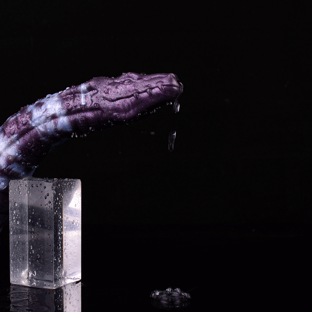 Purple-and-white reptile-pattern dildo head with droplets, over clear container