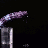Purple-and-white reptile-pattern dildo head with droplets, over clear container