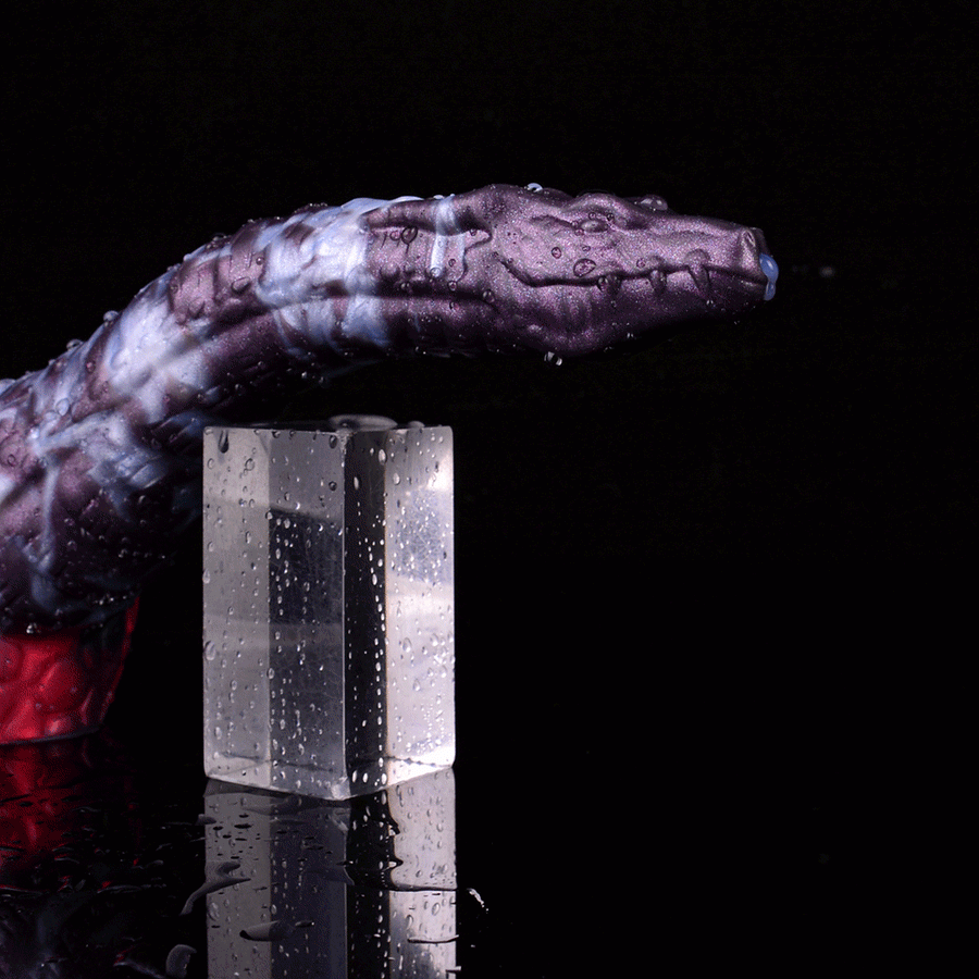 Purple-and-blue patterned dildo with red base splashing water beside clear cylinder