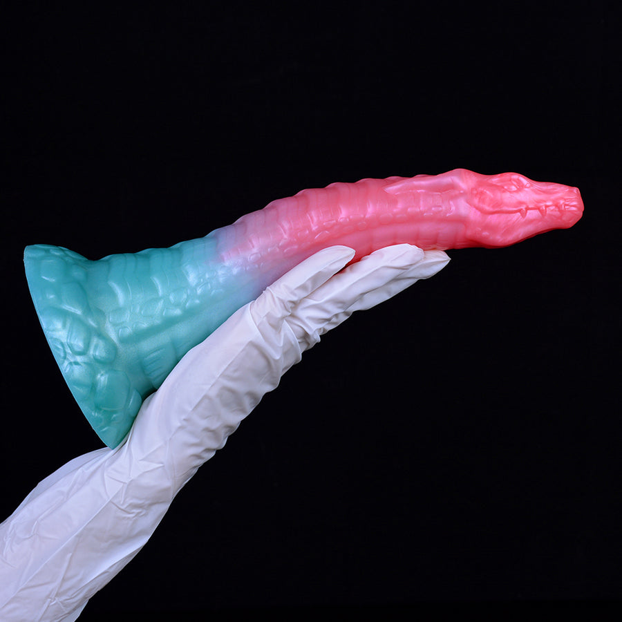 Dragon butt plug in white-gloved hand: pink shaft with teal-blue base, curved