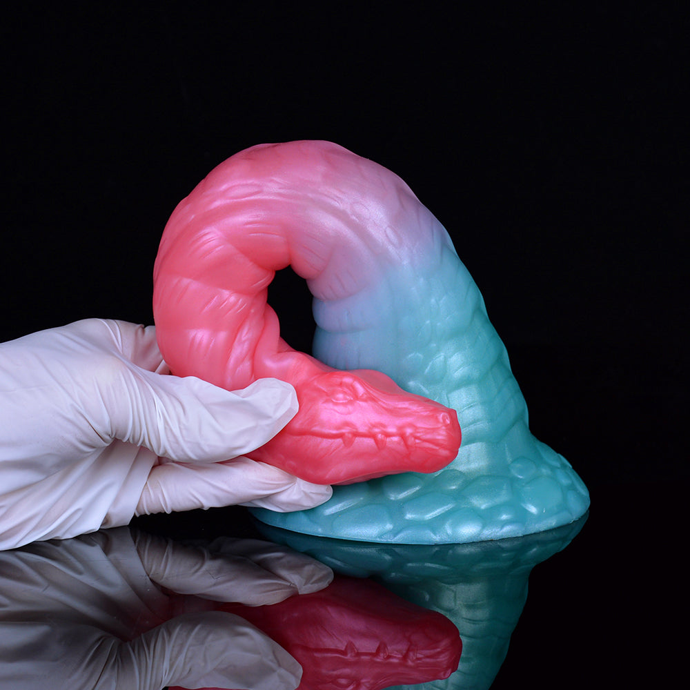 Angled pink-and-teal dildo with flared base, thick curved shaft, raised scale pattern