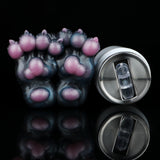 Monster paw-shaped novelty toy with pink toe pads next to silver bottle opener