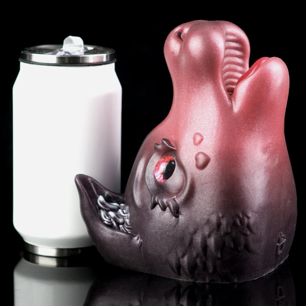 Pink and dark gray cat figurine beside a white container with silver lid
