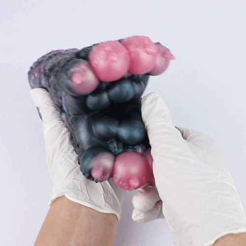 Dark blue and black textured toy with pink nubs, held near a white outfit