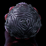 Close-up dark purple silicone octopus head with swirling ridges and small face details