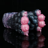 Dark blue and black textured toy with pink end bumps, angled close-up