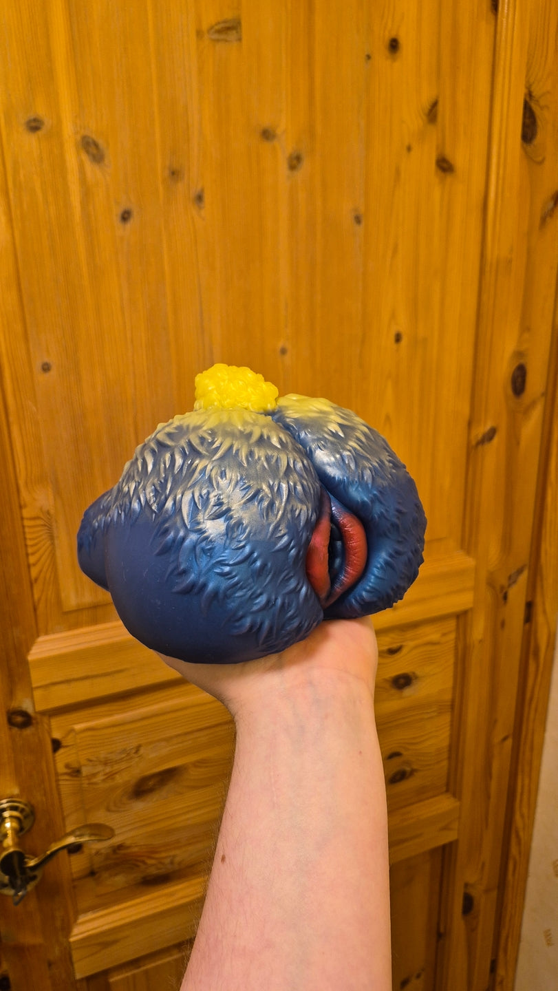 Customer photo of a blue squishy sheep butt fantasy male masturbator with sculpted wool texture, soft silicone cheeks, yellow tail and detailed red lips held in one hand