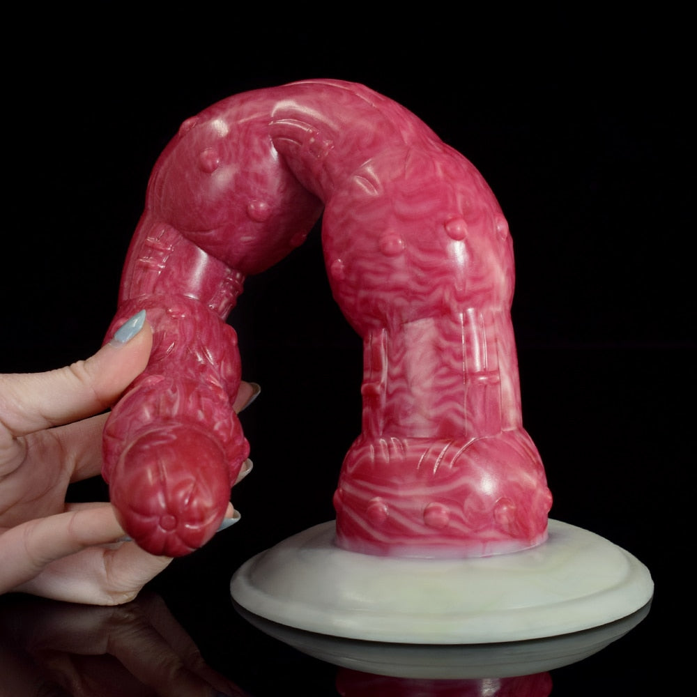 Pink octopus tentacle butt plug near hand, curved with raised bead segments