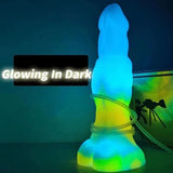 Luminous blue-and-green glowing vibrator in dark, with clear base ring and stem.